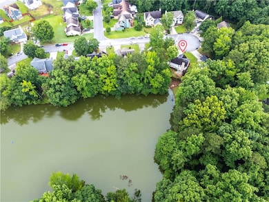 Aerial perspective of suburban area featuring a nearby body of water and a tree filled landscape