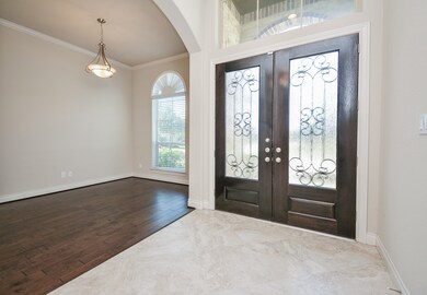 Your elegant front entrance, from the inside, is met with soothing neutral tones on walls with classic crown molding, a raised, 12-foot coffered ceiling and rich wood floors, lining the bright front room, left. Pale tile flooring fills the main hallway/foyer.