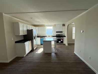 Kitchen with stainless steel appliances, a sink, arched walkways, tasteful backsplash, and white cabinetry
