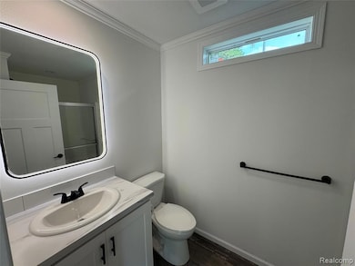 Bathroom with a shower stall, vanity, crown molding, and dark wood-type flooring