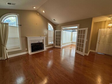 Unfurnished living room featuring wood finished floors, vaulted ceiling, a premium fireplace, a textured ceiling, and baseboards