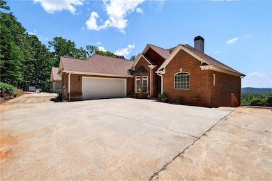 View of front facade with brick siding, driveway, a garage, a chimney, and roof with shingles