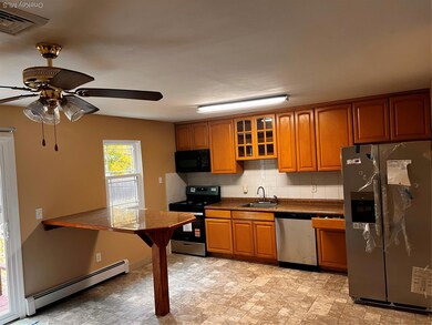 Kitchen featuring fridge, baseboard heating, range, backsplash, and glass insert cabinets