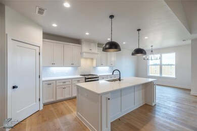 Kitchen with white cabinetry, pendant lighting, ga