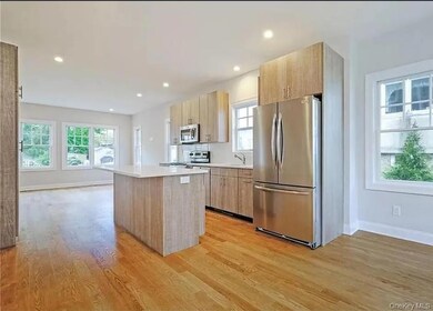 Kitchen with stainless steel appliances, light brown cabinetry, modern cabinets, a kitchen island, and light wood finished floors