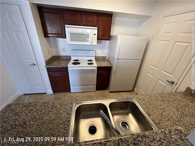Kitchen with white appliances and dark brown cabinetry
