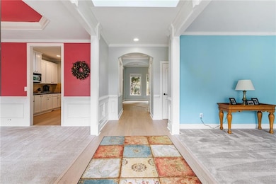 2 Story foyer entrance with arched walkways, ornamental molding, wainscoting, light wood-type flooring, and recessed lighting