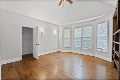 Unfurnished living room with wood finished floors, a ceiling fan, and high vaulted ceiling