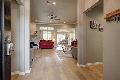 Living area featuring ceiling fan, baseboards, light wood-style floors, a fireplace, and crown molding