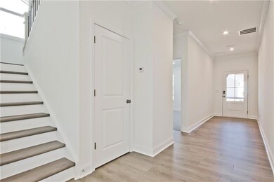 Foyer with light wood-style flooring, crown moldin