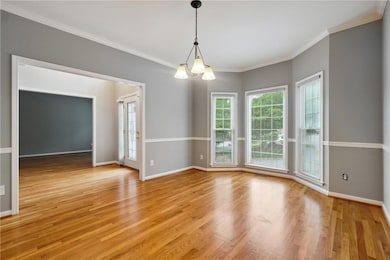 Unfurnished dining area featuring light hardwood / wood-style flooring, crown molding, and a chandelier