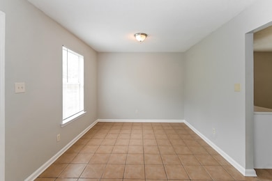 Empty room featuring light tile patterned floors and baseboards