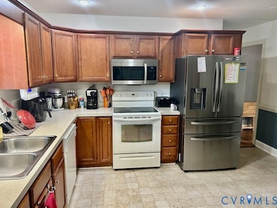 Kitchen featuring stainless steel appliances, light countertops, and brown cabinets