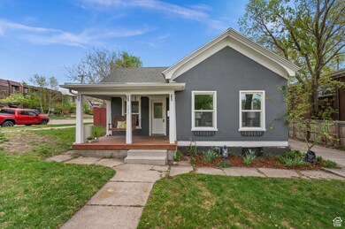 View of front of home featuring a front yard, covered porch, stucco siding, and a shingled roof
