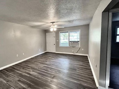 Empty room featuring dark wood-style flooring, ceiling fan, a textured ceiling, and cooling unit
