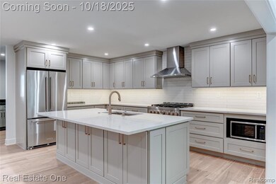 Kitchen with stainless steel appliances, light stone countertops, wall chimney range hood, light wood-type flooring, and decorative backsplash