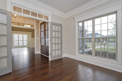 A bright office or formal living room with beautiful hardwood floors and French doors