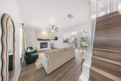 Living area featuring a ceiling fan, stairs, a fi