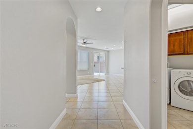 Hall featuring washer / clothes dryer, light tile patterned floors, recessed lighting, and arched walkways