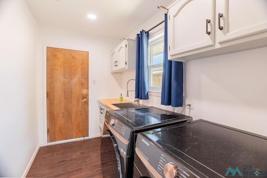 Laundry room with dark wood-style flooring, washing machine and dryer, cabinet space, and recessed lighting