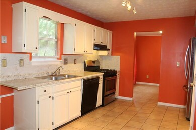 Kitchen featuring stainless steel appliances, under cabinet range hood, backsplash, and light tile patterned floors