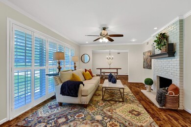 Living room with ornamental molding, brick wall, a brick fireplace, and dark wood-type flooring