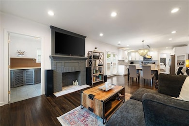 Living area with ornamental molding, a brick fireplace, wood finished floors, and recessed lighting