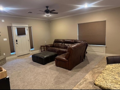 Home theater room with crown molding, a ceiling fan, and light colored carpet