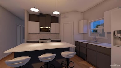 Kitchen featuring a kitchen bar, decorative light fixtures, stainless steel microwave, a sink, and electric range oven