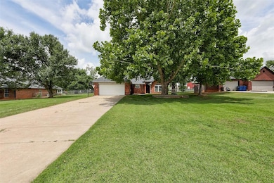 View of property hidden behind natural elements featuring driveway, brick siding, and a front yard