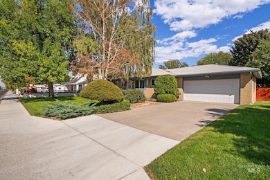 View of front of home featuring brick siding, driveway, a front lawn, and an attached garage