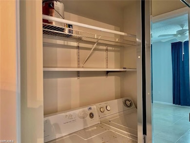 Laundry room with separate washer and dryer, light tile patterned floors, and ceiling fan