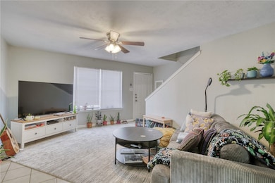 Tiled living area with a ceiling fan and a textured ceiling