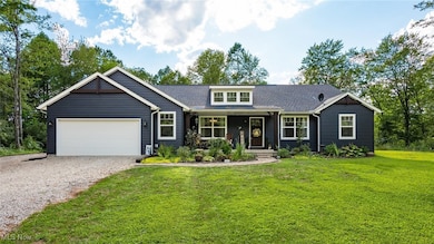 View of front facade with gravel driveway, covered porch, an attached garage, and a front yard