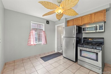 Kitchen featuring appliances with stainless steel finishes, light tile patterned flooring, brown cabinets, and ceiling fan