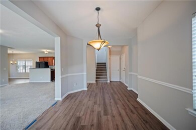 Unfurnished dining area with stairs, dark wood-style floors, and baseboards