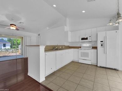 Kitchen with a sink, a peninsula, white appliances