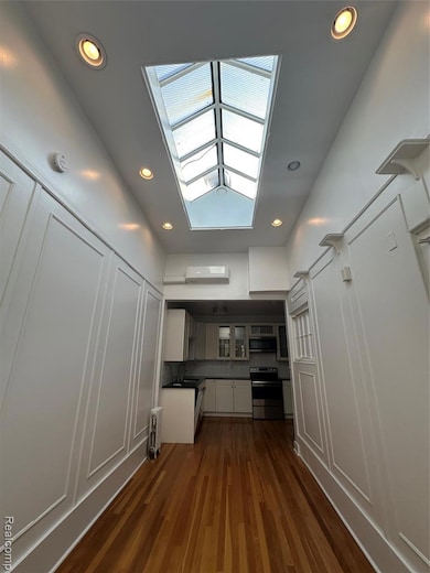 Kitchen with white cabinetry, recessed lighting, glass insert cabinets, range, and dark countertops