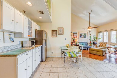 Kitchen featuring white cabinets, light countertops, light tile patterned floors, white microwave, and freestanding refrigerator