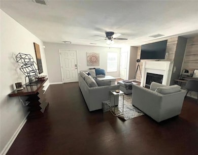 Living room with ceiling fan, dark wood-style floo