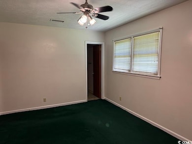 Primary Bedroom with ceiling fan, a textured ceiling, and dark carpet