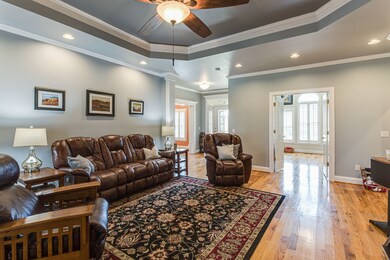 The Great Room has double tray ceiling with ceiling fan. This view shows the foyer and the French Doors opening to the separate den.