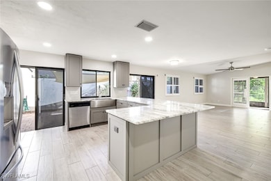 Kitchen offers light gray custom cabinetry with bu