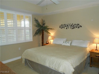 Carpeted bedroom with a ceiling fan and baseboards