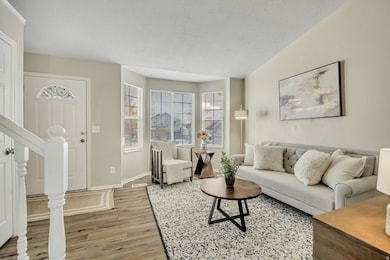 Living area featuring a textured ceiling, light wood-style floors, and stairway