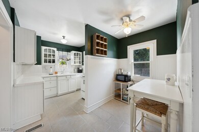 Kitchen featuring tile countertops, backsplash, light tile flooring, sink, and ceiling fan