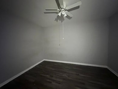 Unfurnished room featuring dark wood finished floors and a ceiling fan