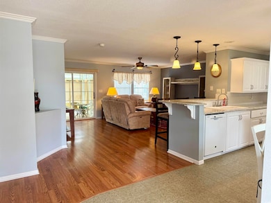 Kitchen with white dishwasher, a sink, ornamental molding, a kitchen bar, and white cabinetry