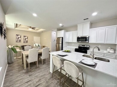 Kitchen with white cabinets, stainless steel appliances, light stone countertops, dark wood finished floors, and recessed lighting
