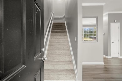 Staircase with wood finished floors, crown molding